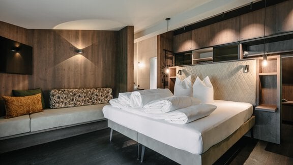 A modern bedroom with a large bed and fresh towels. A cozy seating area complements the elegant room. - VIBES Sölden - your alpine homebase - Sölden