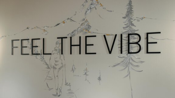 A wall with the inscription "FEEL THE VIBE" and a sketchy depiction of mountains and trees. The illustration conveys a sense of nature and the outdoors. - VIBES Sölden - your alpine homebase - Sölden