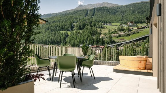 A terrace with modern outdoor furniture and an outdoor bathtub, including a view of the mountains and the valley. The surroundings are green and sunny, ideal for relaxing. - VIBES Sölden - your alpine homebase - Sölden