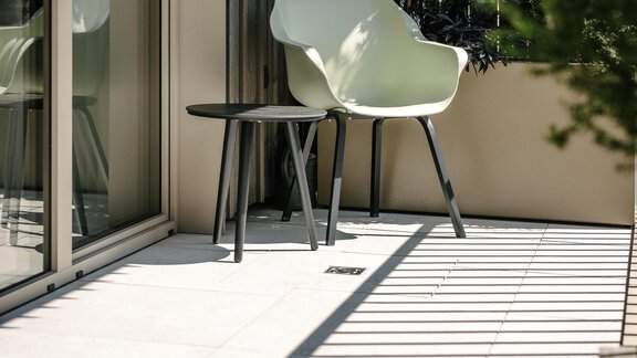 A stylish balcony with a modern chair and a small table surrounded by green plants. - VIBES Sölden - your alpine homebase - Sölden