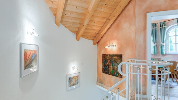 An elegant staircase with a wooden ceiling and artworks on the walls. The room is bright and inviting. - Villa Castelbell - Sölden