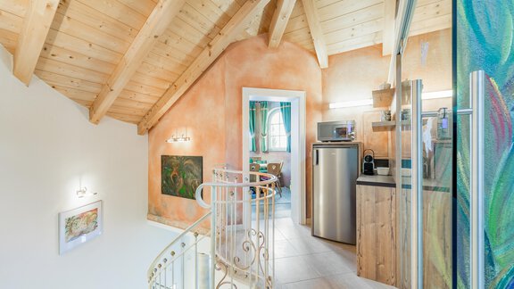 A modern kitchen with wooden surfaces and an open living area. The wooden roof structure gives the space a cozy atmosphere. - Villa Castelbell - Sölden