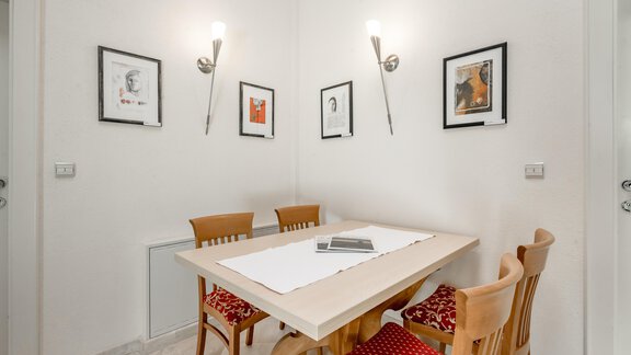 A bright dining area with a wooden table and four chairs. Several pictures hang on the wall, and the lighting creates a cozy atmosphere. - Villa Castelbell - Sölden