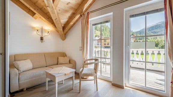 A cozy living space with a bright sofa and a small table. Large windows offer a view of the surrounding mountains. - Villa Castelbell - Sölden