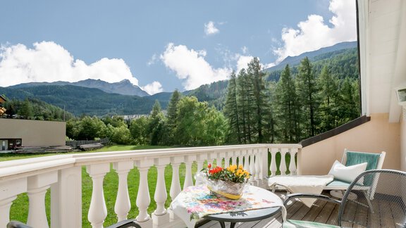 A balcony with a beautiful view of mountains and trees. A table with flowers and chairs invites you to relax. - Villa Castelbell - Sölden
