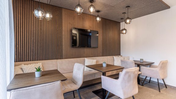 A modern café with cozy seating areas and stylish lamps. There is a television on one wall, and the atmosphere is inviting and bright. - Vizensn Living - Sölden