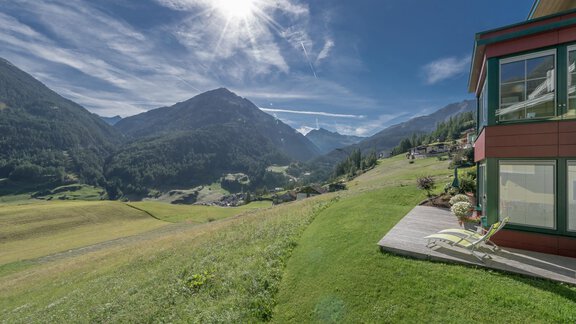 An idyllic landscape with green meadows and mountains in the background. The sky is clear and sunny, and a building stands in the foreground. - zuckerhütl NATURAPPART - Sölden