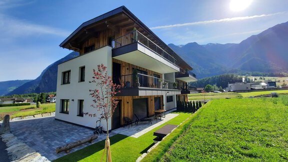 Ein modernes Gebäude in einer malerischen Landschaft. Umgeben von Bergen und grünem Rasen bietet es eine ruhige Atmosphäre. - Apart Dorhoam - Umhausen