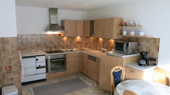 A modern kitchen with wooden cabinets and stainless steel appliances. The room is bright and inviting, with a dining table in the corner. - Apart Martina - Umhausen