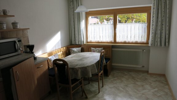 A bright kitchen with a round table and chairs. The windows let in plenty of daylight. - Apart Martina - Umhausen