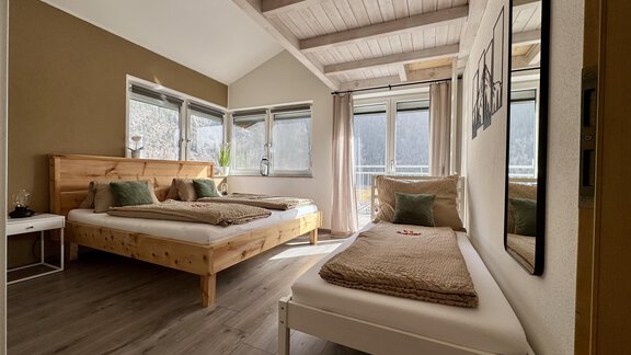 Ein gemütliches Schlafzimmer mit zwei Betten und großen Fenstern. Die warmen Farben und die Holzdetails schaffen eine einladende Atmosphäre. - Appartement Bergglück - Umhausen