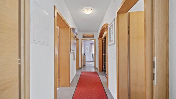 A bright hallway with wooden frames and a red runner. Several doors lead to additional rooms. - Biancas Ferienwohnung im Haus Roswitha - Umhausen