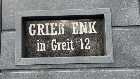 Ein auffälliges Schild mit der Aufschrift „GRIEß ENK in Greit 12“. Das Schild ist aus dunklem Material und befindet sich an einer Wand. - BLANKA'S Apart Auszeit - Umhausen