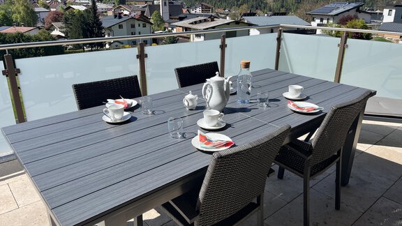 Ein schöner Tisch auf einer Terrasse mit Blick auf die Berge. Der Tisch ist gedeckt mit Porzellan und Gläsern für eine gemütliche Mahlzeit. - BLANKA'S Apart Auszeit - Umhausen