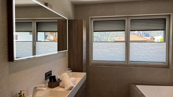 Ein modernes Badezimmer mit einem stilvollen Spiegel und einer Badewanne. Die hellen Wände und Fenster sorgen für eine angenehme Atmosphäre. - BLANKA'S Apart Auszeit - Umhausen