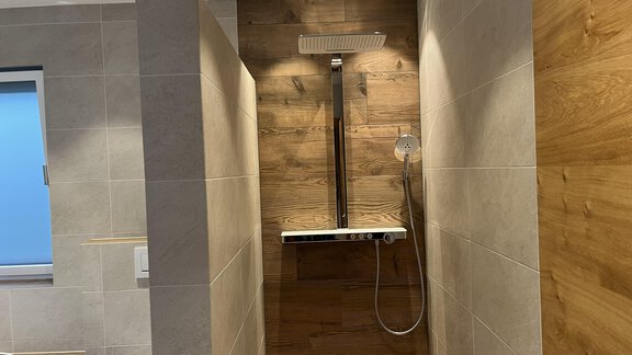 Moderne Dusche mit Holz- und Fliesenakzenten. Helle Beleuchtung und elegante Armaturen schaffen eine einladende Atmosphäre. - BLANKA'S Apart Auszeit - Umhausen