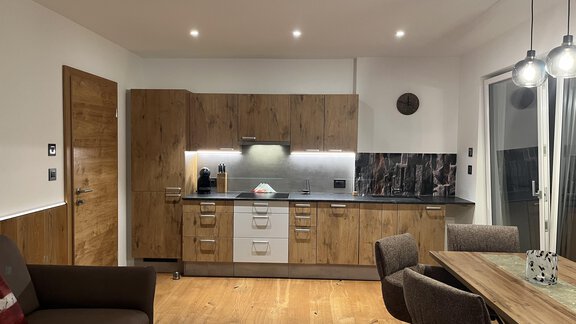 Eine moderne Küche mit Holzschränken und einer eleganten Arbeitsfläche. Der Essbereich ist gemütlich eingerichtet und gut beleuchtet. - BLANKA'S Apart Auszeit - Umhausen
