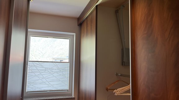 A modern wardrobe with wood paneling. A window provides natural light and a pleasant atmosphere. - BLANKA'S Apart Auszeit - Umhausen