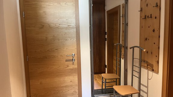 Ein Flur mit einer Holzttür, einem großen Spiegel und einem Sitzplatz. An der Wand befindet sich eine Garderobe. - BLANKA'S Apart Auszeit - Umhausen