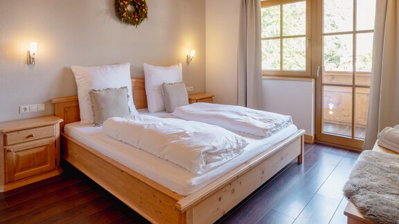 A cozy bedroom with two single beds and wooden-paneled walls. The room has large windows that offer a view outside. - Chalet Carla - Umhausen