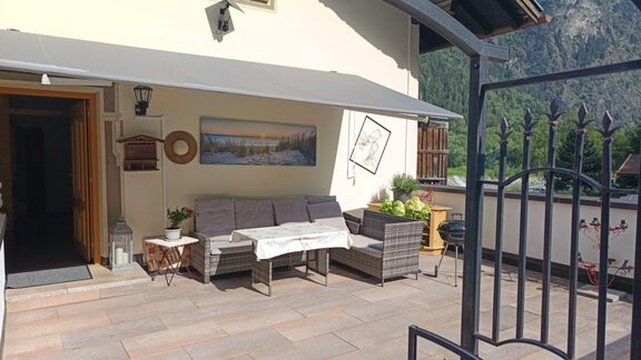 A cozy terrace with wooden furniture and a beautiful view of the mountains. The decor is modern and inviting, perfect for relaxing hours outdoors. - Ferienwohnung Martha - Umhausen