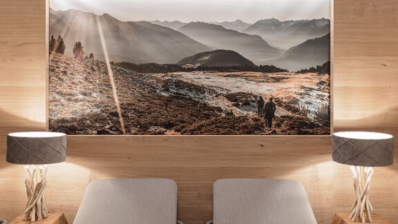Ein gemütlicher Raum mit zwei Liegen und sanftem Licht. An der Wand hängt ein großes Landschaftsbild der Berge im Sonnenlicht. - MYALPS Ötztal - Umhausen
