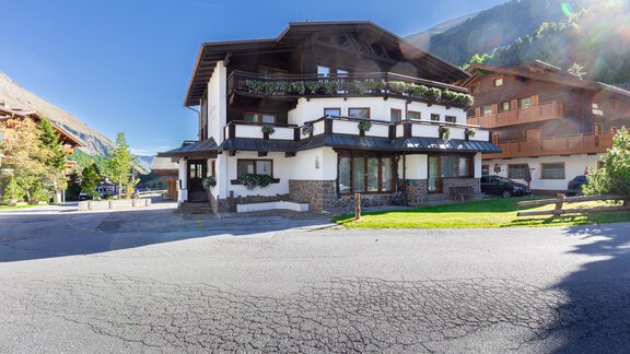A modern building in alpine style with many windows and balustrades.  
Surrounded by a picturesque landscape with mountains and green spaces. - Garni Stefani - Vent