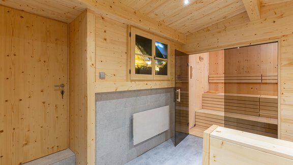 A cozy wellness area with wood paneling and a sauna. Large windows let warm light in. - Garni Stefani - Vent
