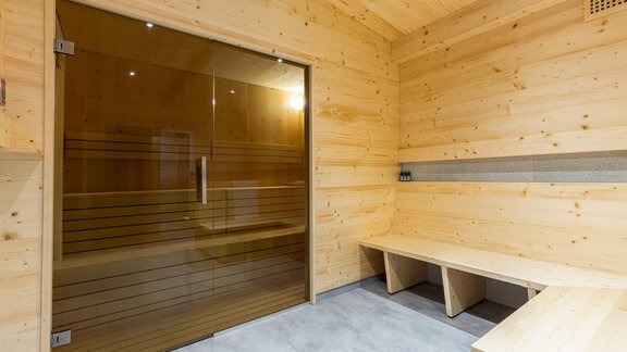 A modern sauna with large glass fronts and wooden paneling. The benches are made of light wood, and the room feels welcoming and relaxing. - Garni Stefani - Vent