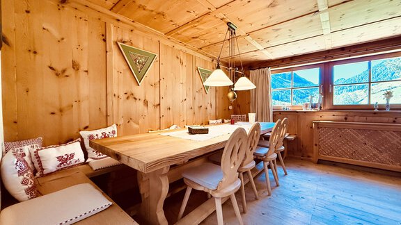 A cozy wooden table with chairs in a rustic room. Large windows offer a view of the surrounding nature. - Haus Freistabl - Vent