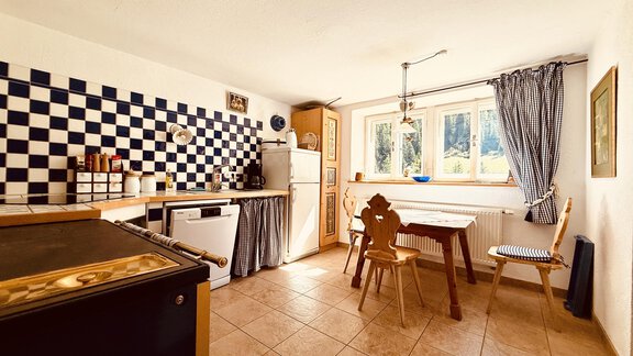 A bright kitchen with a checkered tile design and a cozy dining area. Large windows bring in light and a view of the outdoors. - Haus Freistabl - Vent