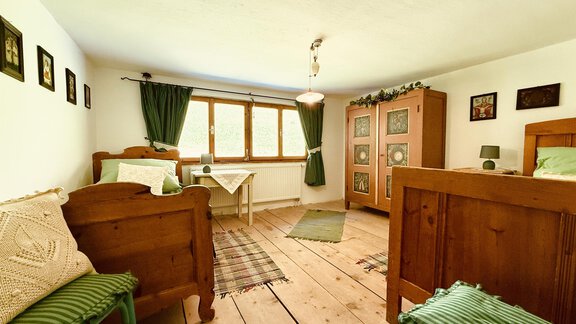 A cozy room with wooden flooring and traditional furnishings. Bright curtains and the windows provide plenty of daylight. - Haus Freistabl - Vent