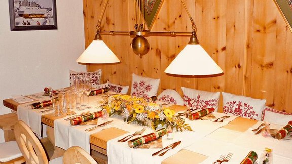 A cozy dining table in a wood-paneled room, festively set with flowers and cutlery. The atmosphere is inviting and warm. - Haus Freistabl - Vent