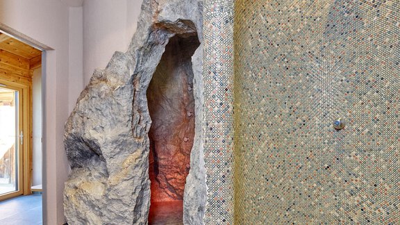 A modern wellness area with a rocky entrance to a steam bath. The wall is decorated with colorful mosaic tiles. - Hotel Vent - Vent
