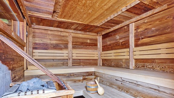 A cozy wooden sauna with benches and a stove. The room radiates relaxation and warmth. - Hotel Vent - Vent
