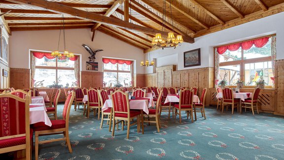 A cozy restaurant with wooden beam ceiling and red chairs. The large windows offer a beautiful view of the landscape. - Hotel Vent - Vent