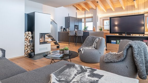 A modern living room with comfortable seating and a fireplace. The open kitchen and large windows create a bright, inviting atmosphere. - Weinleins Hof - Vent