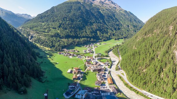 A picturesque mountain landscape with a small village in the valley. The surroundings are green and surrounded by high mountains. - Garni Ötztal ROOMS & APARTS - Zwieselstein