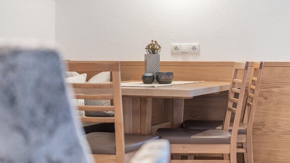 A modern dining area with a wooden table and chairs. Decorative elements such as plants and candles are placed on the table. - Garni Ötztal ROOMS & APARTS - Zwieselstein