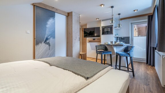 A modern room with a double bed and a small kitchenette. The room has a bright, inviting style and large window light. - Garni Ötztal ROOMS & APARTS - Zwieselstein