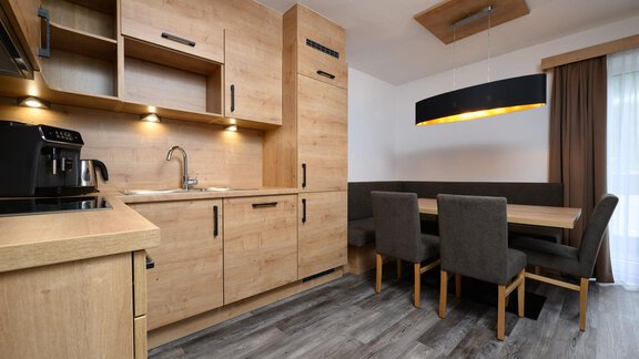 A modern kitchen with wooden cabinets and a corner dining area. The room is bright and inviting with elegant furniture. - Gästehaus Judith - Zwieselstein