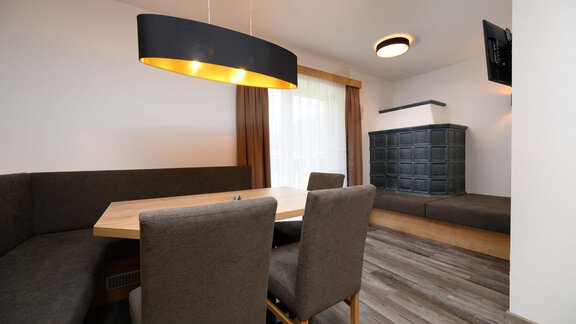 A modern dining room with a large table group and comfortable chairs. The walls are painted in light colors and there is an elegant ceiling spotlight. - Gästehaus Judith - Zwieselstein
