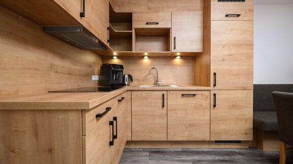 A modern kitchen made of light wood with elegant black fittings. It is well-equipped and has a cozy atmosphere. - Gästehaus Judith - Zwieselstein