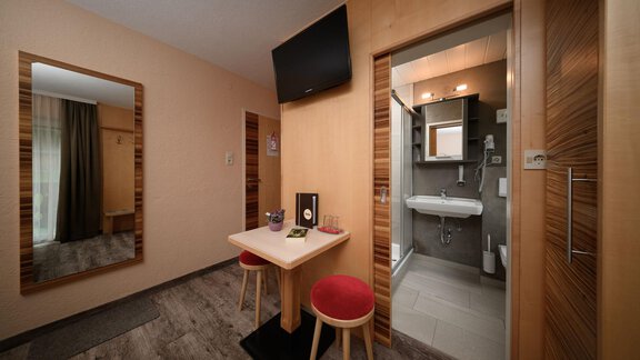 A modern room with wooden details and a small dining area. The bathroom is separated by a door and offers modern amenities. - Haus Sonnschein - Zwieselstein