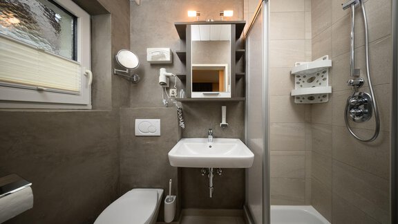 A modern bathroom with a shower and sink. The walls are in neutral shades and there is a large mirror. - Haus Sonnschein - Zwieselstein