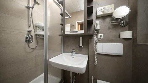 A modern bathroom with a shower cabin and a sink. The walls are in neutral tones, and there are practical details such as a mirror and holders. - Haus Sonnschein - Zwieselstein