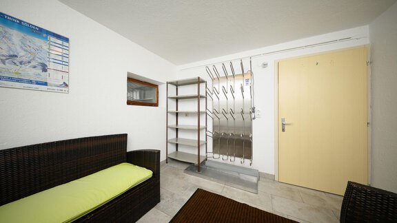 A cozy entrance area with a sofa and a shelf.  
On the wall hangs a map, and the door leads outside. - Haus Sonnschein - Zwieselstein