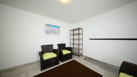 A simple room with two chairs and a shelf. The walls are white and the floor has a light covering. - Haus Sonnschein - Zwieselstein