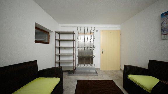 A bright entrance area with two dark sofas and green cushions. In the background, there is a shelf and a door leading to another room. - Haus Sonnschein - Zwieselstein