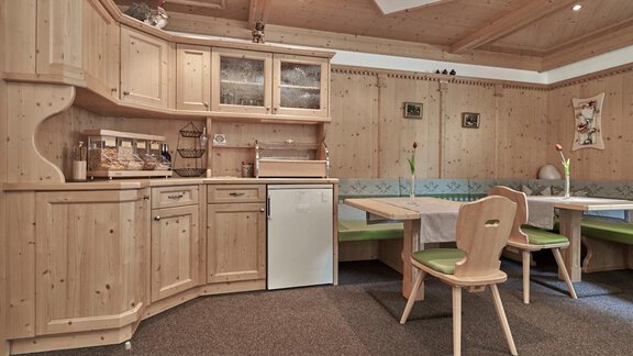 A bright kitchen with wooden cabinets and a small dining area. The room is cozily furnished and invites you to linger. - Haus Sonnschein - Zwieselstein